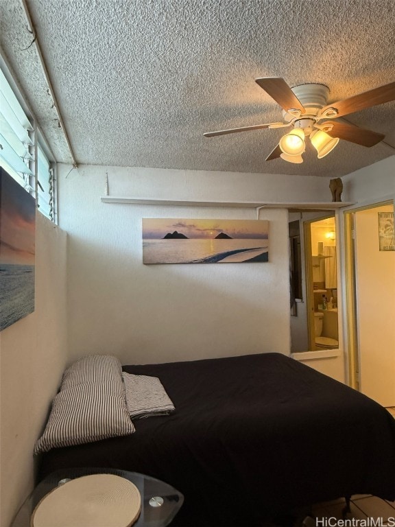 bedroom with ceiling fan, ensuite bathroom, and a textured ceiling