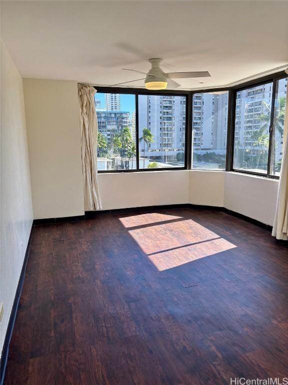 empty room with dark wood-type flooring and ceiling fan