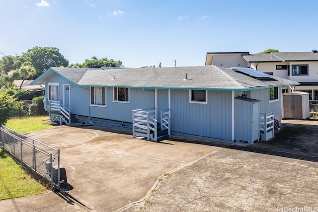 rear view of property with a shed and solar panels