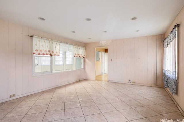 tiled spare room featuring wood walls