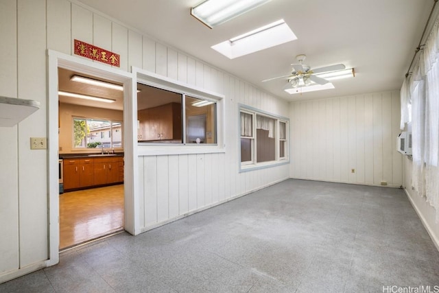 unfurnished room with ceiling fan, sink, and a skylight