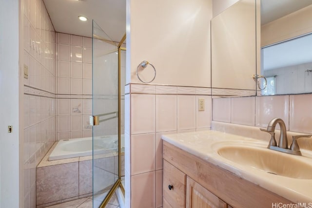 bathroom with combined bath / shower with glass door, vanity, and tile walls