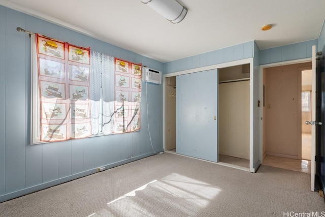 unfurnished bedroom with light carpet, a wall mounted AC, and a closet