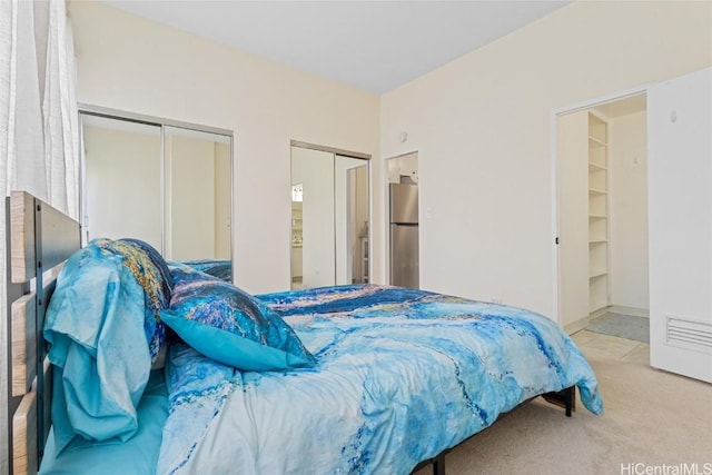 bedroom featuring light colored carpet and stainless steel refrigerator