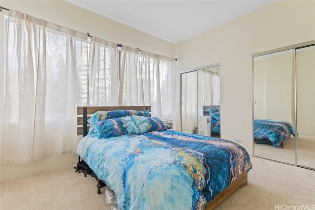 bedroom featuring light carpet and multiple closets