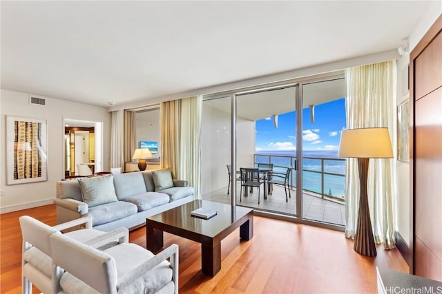 living room featuring expansive windows, a water view, and light hardwood / wood-style flooring