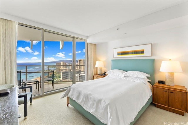 bedroom with expansive windows, a water view, light carpet, and access to outside