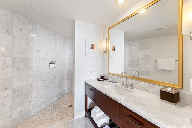 bathroom with a tile shower and vanity