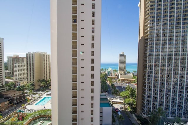 view of building exterior with a water view, a community pool, and a city view