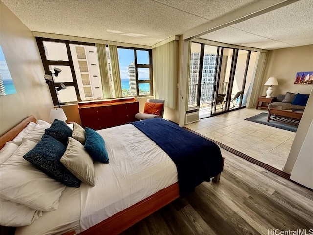 bedroom featuring light wood-type flooring, access to exterior, a water view, and a textured ceiling