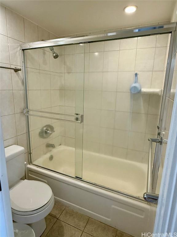 full bathroom featuring combined bath / shower with glass door, tile patterned flooring, and toilet