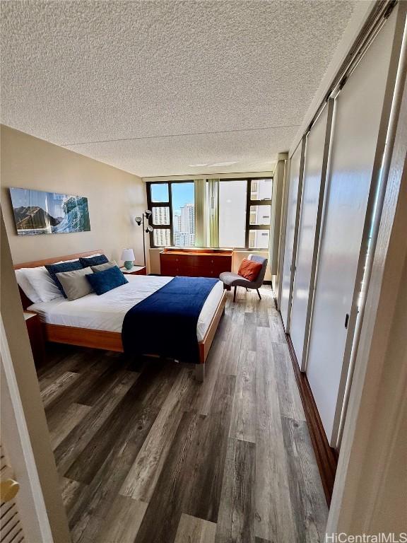 bedroom with a closet, dark wood finished floors, and a textured ceiling