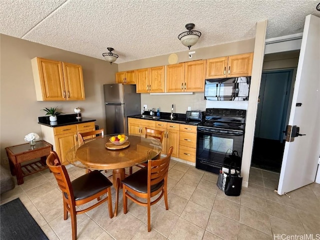 kitchen with black appliances, light brown cabinetry, and dark countertops