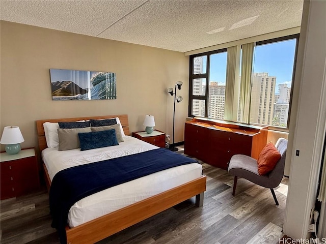 bedroom with a view of city, a textured ceiling, and wood finished floors