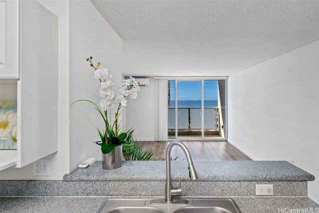 kitchen with sink, a wall of windows, a textured ceiling, and a wall unit AC