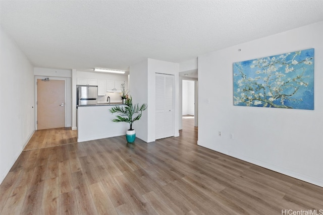 unfurnished living room featuring a textured ceiling and light hardwood / wood-style floors