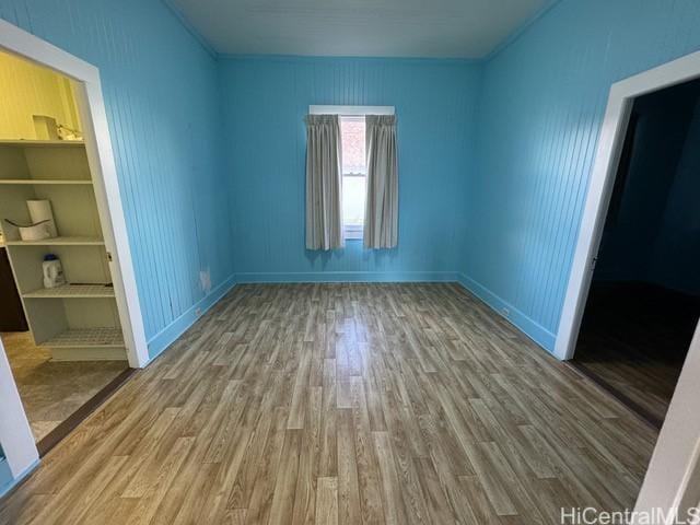 unfurnished room with built in shelves and wood-type flooring