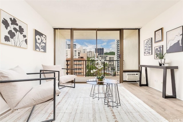 living area featuring an AC wall unit, light wood-type flooring, and a wall of windows