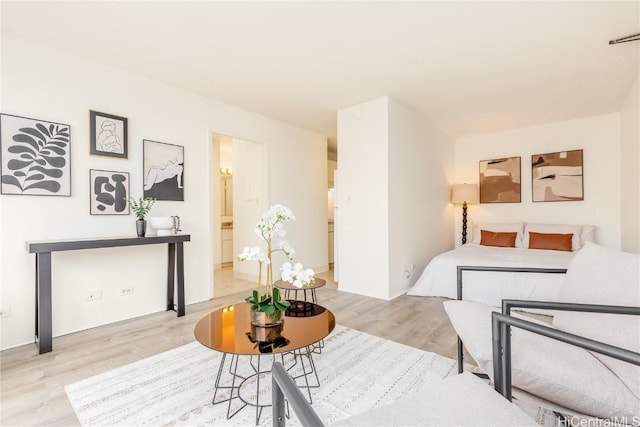 bedroom with connected bathroom and light hardwood / wood-style flooring