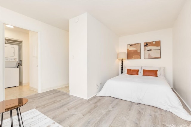 bedroom with light hardwood / wood-style flooring and stacked washer / drying machine