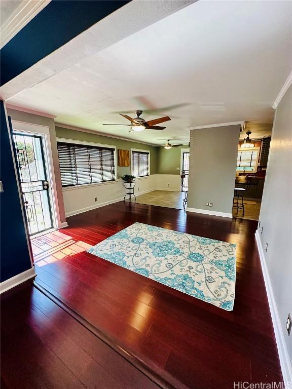 unfurnished living room with ornamental molding, plenty of natural light, dark hardwood / wood-style floors, and ceiling fan