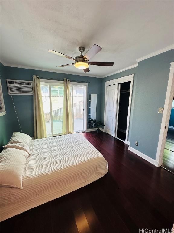 bedroom with dark wood-type flooring, crown molding, a wall mounted AC, a closet, and access to exterior