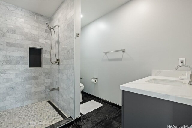 bathroom featuring vanity, toilet, and a tile shower