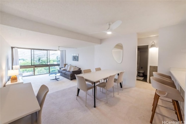 dining area featuring ceiling fan, expansive windows, and light colored carpet