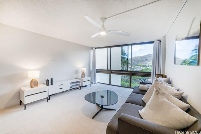 living room featuring floor to ceiling windows, ceiling fan, light colored carpet, and a textured ceiling