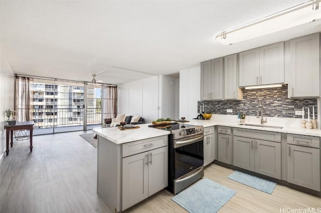 kitchen with expansive windows, electric stove, sink, gray cabinets, and kitchen peninsula