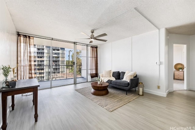 sitting room with floor to ceiling windows, ceiling fan, light hardwood / wood-style flooring, and a textured ceiling