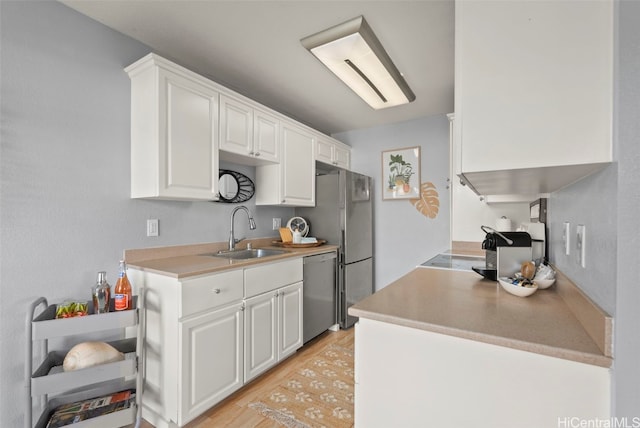 kitchen with sink, light hardwood / wood-style flooring, stainless steel dishwasher, and white cabinets