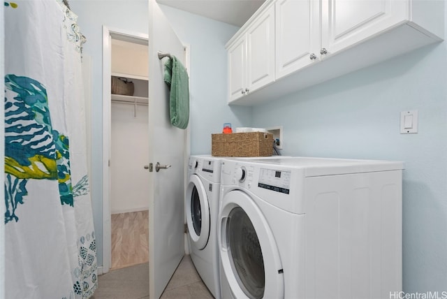 laundry room with cabinets, light tile patterned floors, and washer and dryer