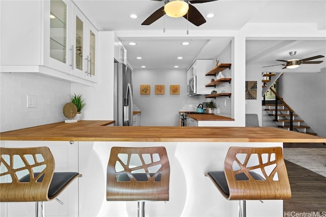 bar featuring appliances with stainless steel finishes, butcher block countertops, white cabinetry, and tasteful backsplash