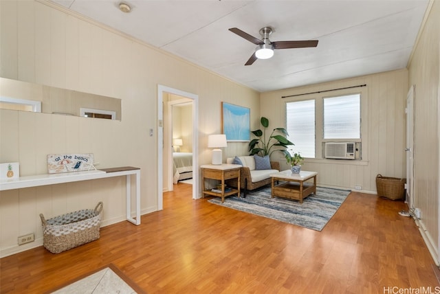 sitting room featuring ceiling fan, wooden walls, cooling unit, and hardwood / wood-style flooring