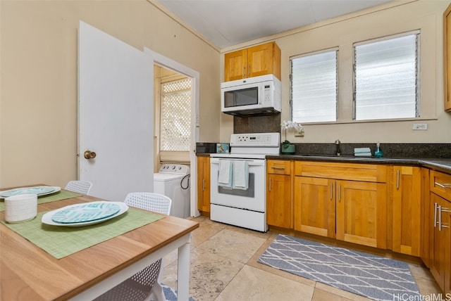 kitchen featuring light tile patterned floors, white appliances, washer / clothes dryer, and sink