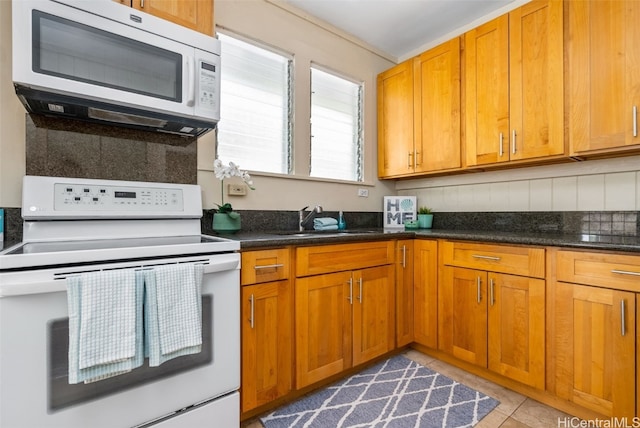 kitchen with decorative backsplash, light tile patterned flooring, white appliances, and sink