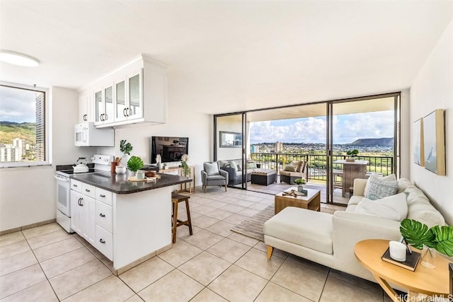 kitchen featuring white cabinetry, kitchen peninsula, white appliances, a breakfast bar area, and light tile patterned floors