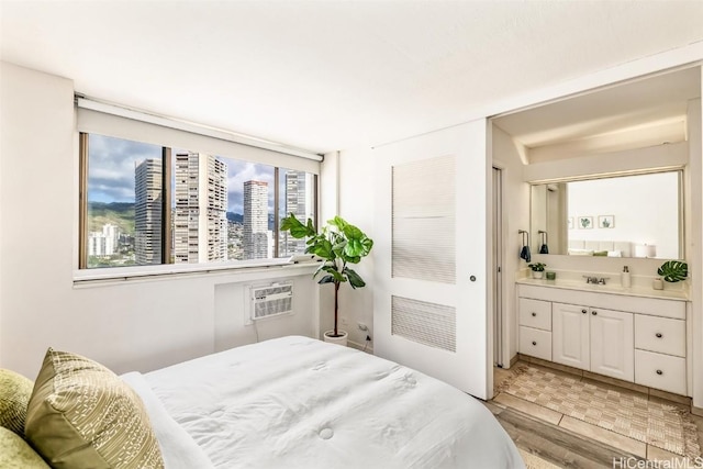 bedroom featuring light hardwood / wood-style floors, an AC wall unit, and sink