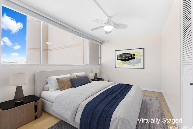 bedroom featuring light wood-style flooring, a ceiling fan, a closet, and baseboards