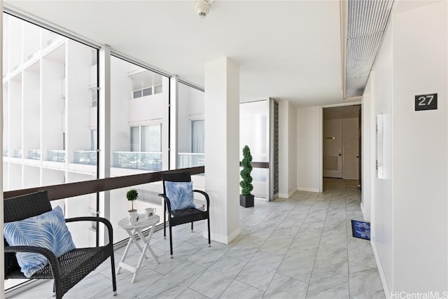 hall with marble finish floor, baseboards, and expansive windows