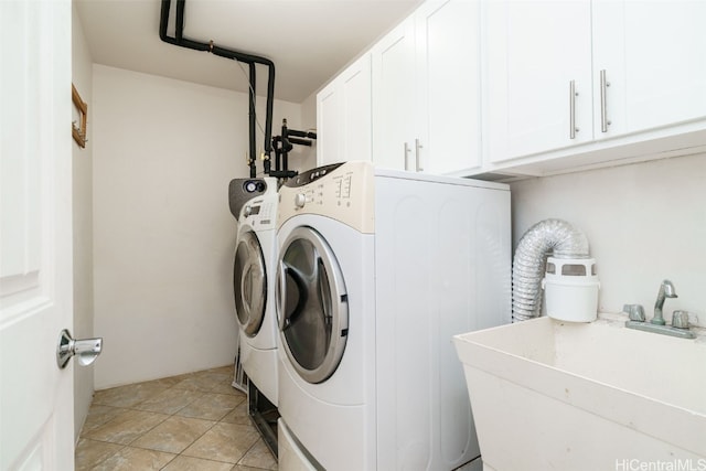 laundry area featuring washing machine and dryer, sink, light tile patterned floors, and cabinets