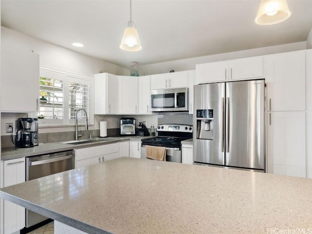 kitchen with hanging light fixtures, sink, white cabinets, and stainless steel appliances