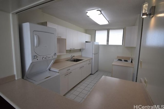 kitchen featuring white cabinets, white fridge, sink, and stacked washer / dryer