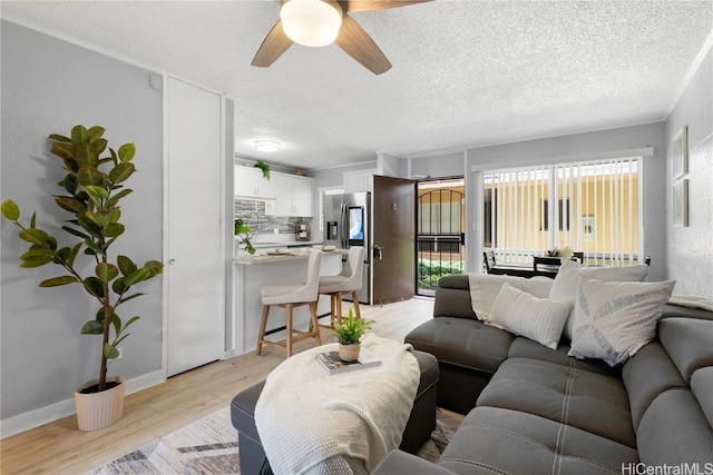 living room featuring ceiling fan, a textured ceiling, and light wood-type flooring