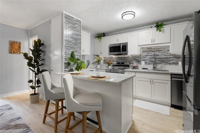 kitchen featuring sink, light hardwood / wood-style flooring, white cabinets, and appliances with stainless steel finishes