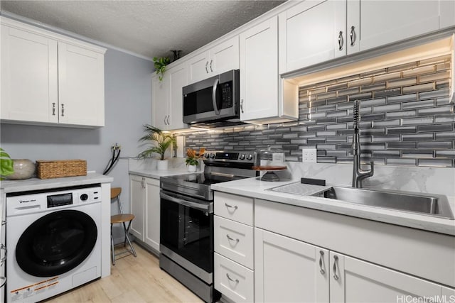 kitchen featuring washer / dryer, sink, white cabinetry, appliances with stainless steel finishes, and backsplash