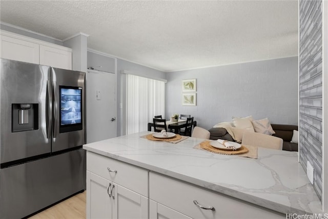 kitchen featuring stainless steel refrigerator with ice dispenser, light wood-type flooring, white cabinets, and light stone counters