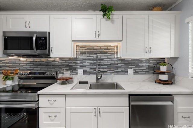 kitchen featuring stainless steel appliances, sink, white cabinets, and light stone counters