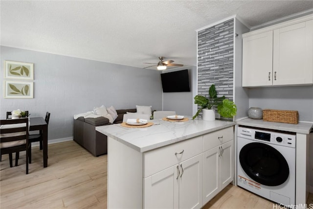 kitchen with white cabinetry, washer / dryer, kitchen peninsula, a textured ceiling, and light hardwood / wood-style flooring